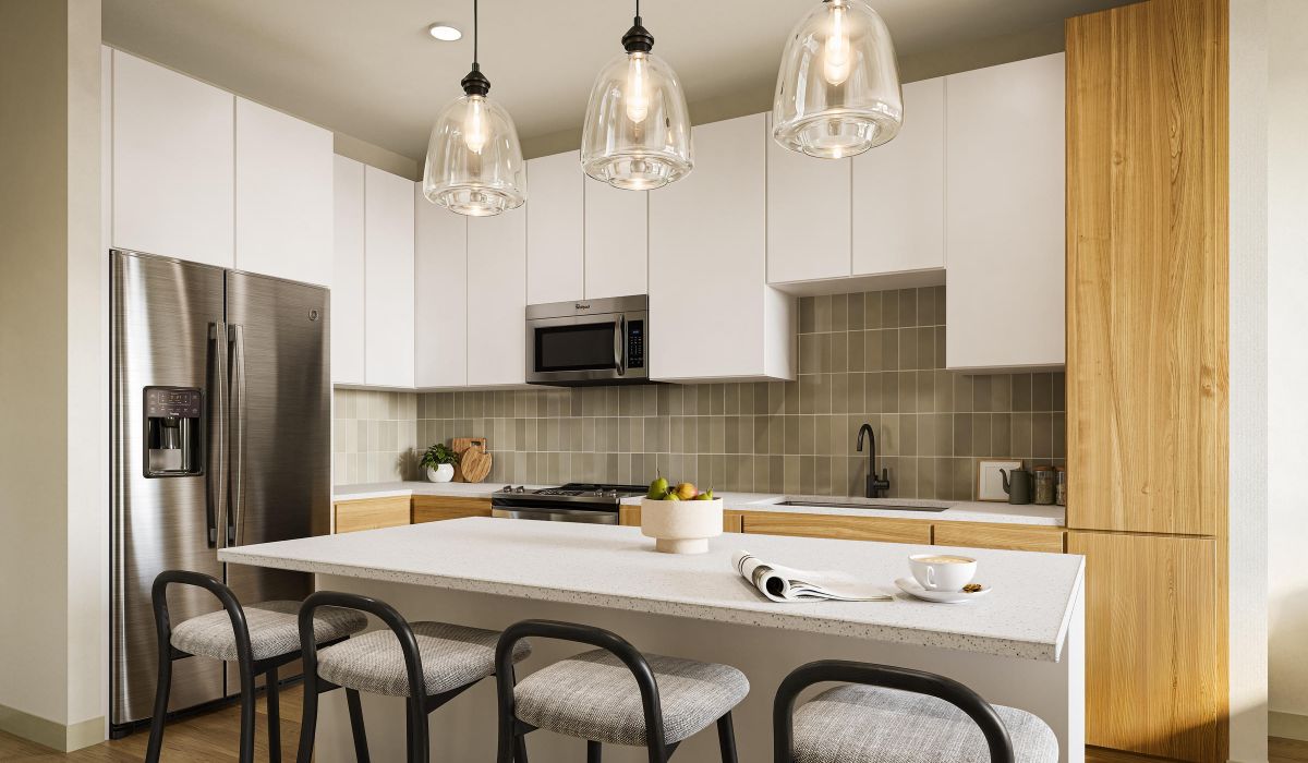 Modern kitchen with an island, pendant lights, white cabinets, wood accents, and stainless steel appliances.