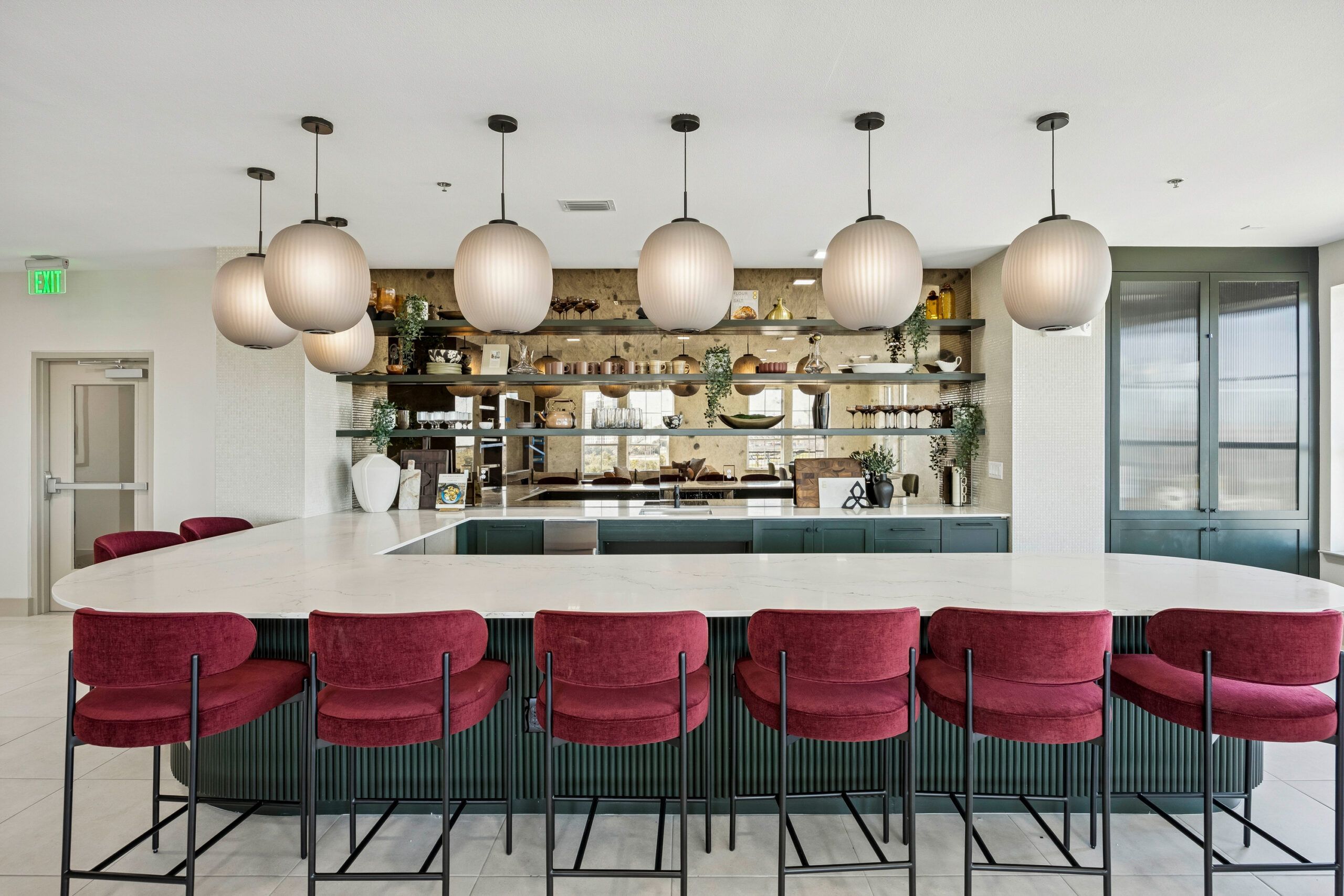 Modern kitchen with a white island, red barstools, pendant lights, and open shelves with decor.