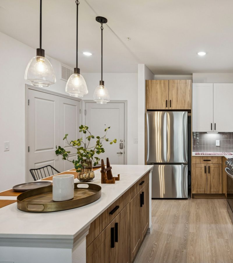 Modern kitchen with wood and white cabinets, stainless steel appliances, and pendant lights over an island.