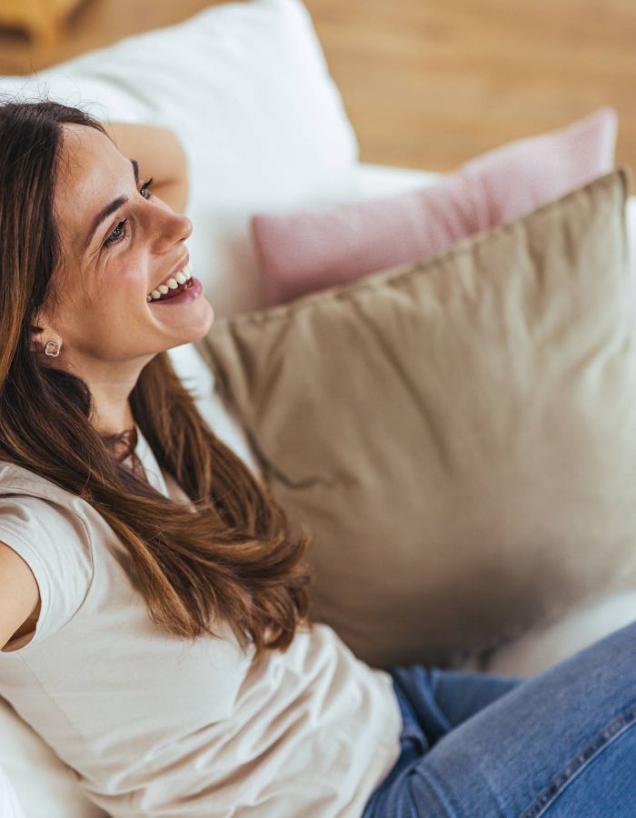 Smiling woman relaxing on a couch with a glucose monitor on her upper arm.