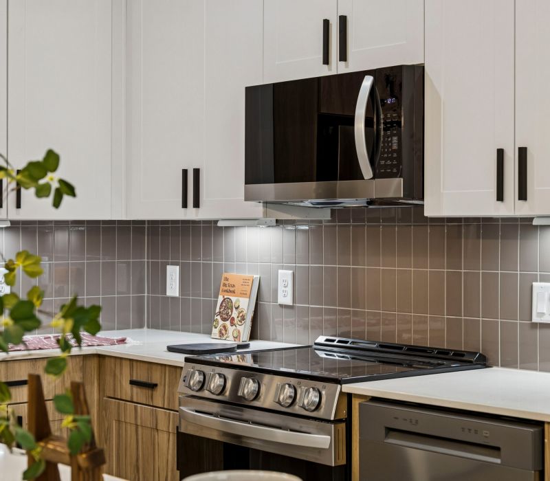 Modern kitchen with white cabinets, stainless steel appliances, and a cookbook on the counter.