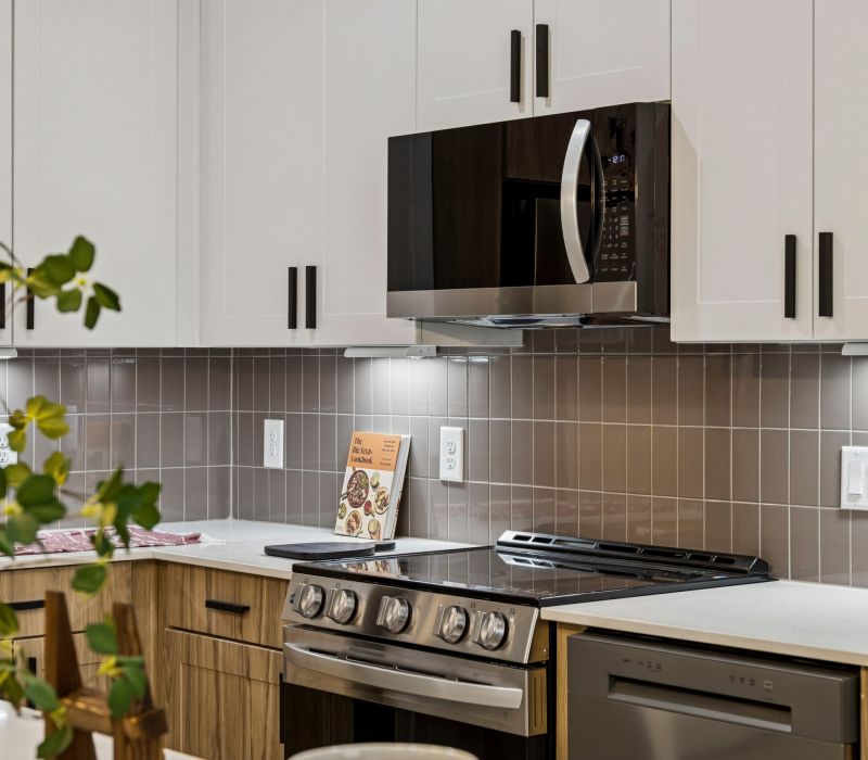 Modern kitchen with white cabinets, stainless steel appliances, and a cookbook on the counter.